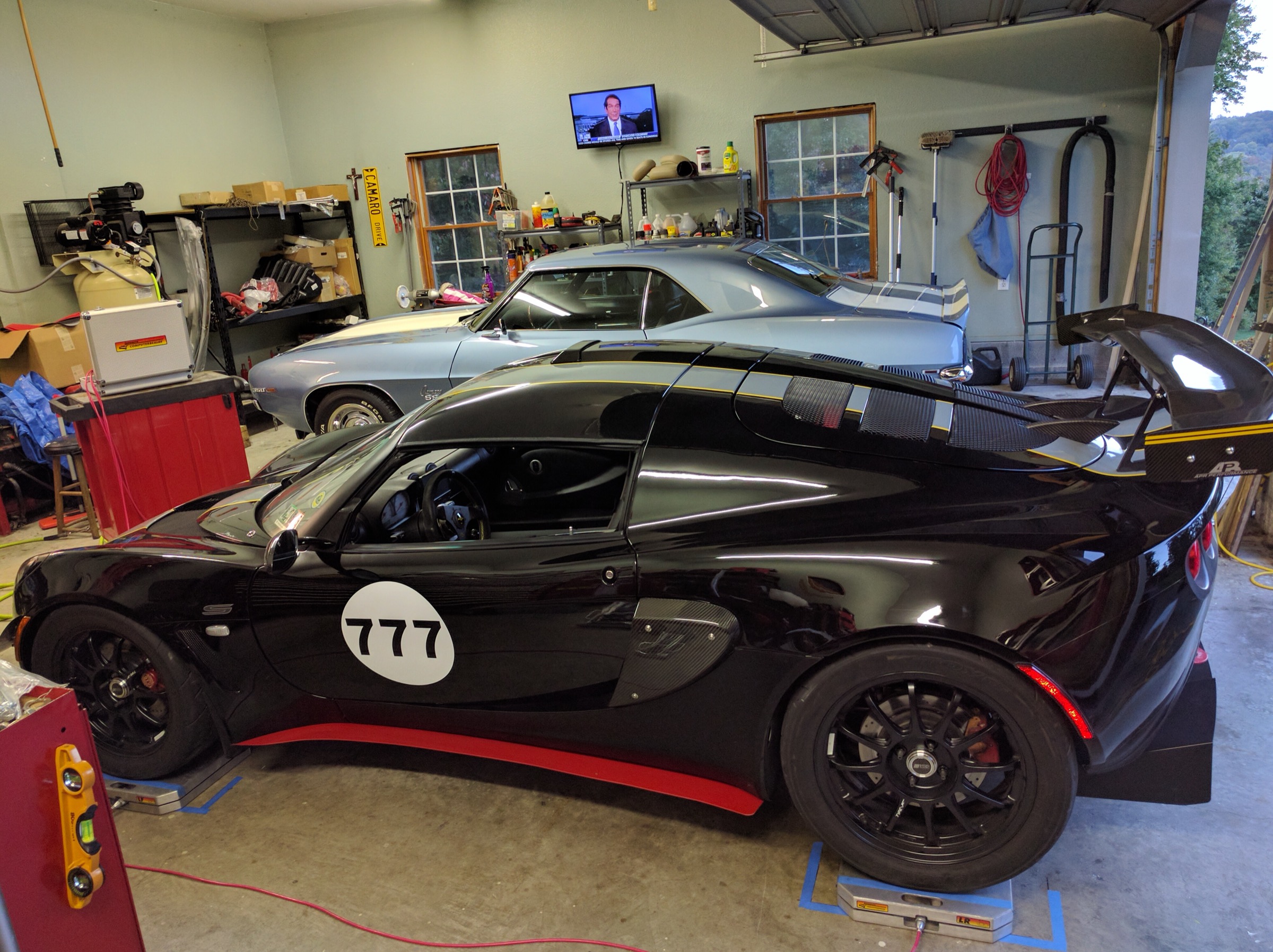Lotus Exige number 777 sitting on corner-balance scale pads in a workshop