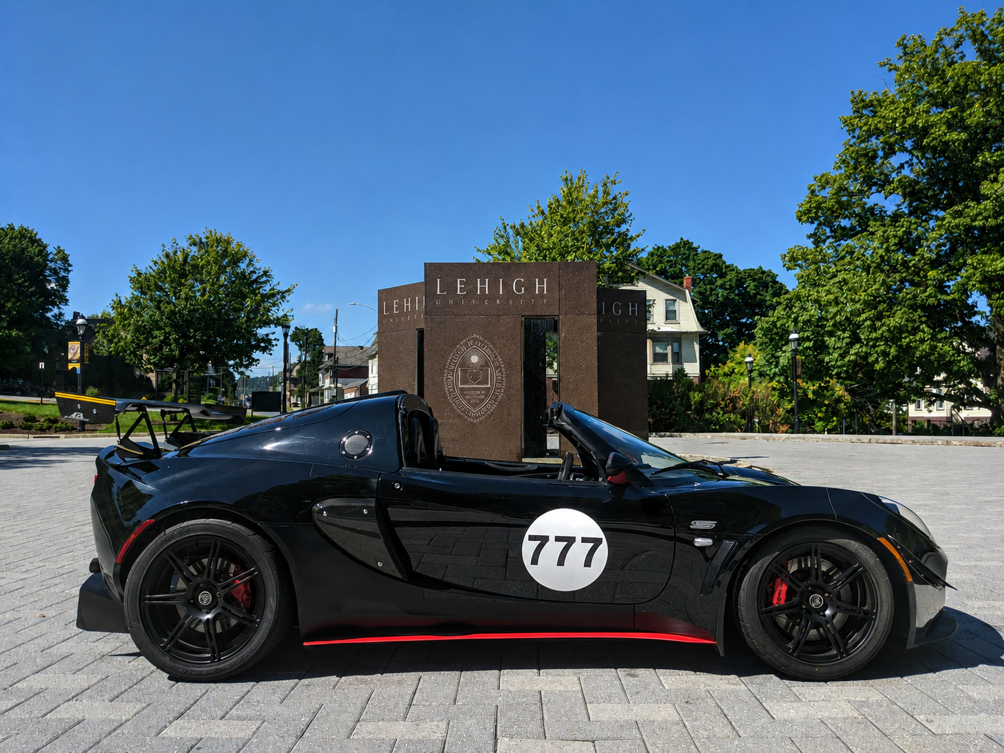Black Lotus Exige number 777 in profile, parked in front of the LEHIGH stone monument on Lehigh University's campus