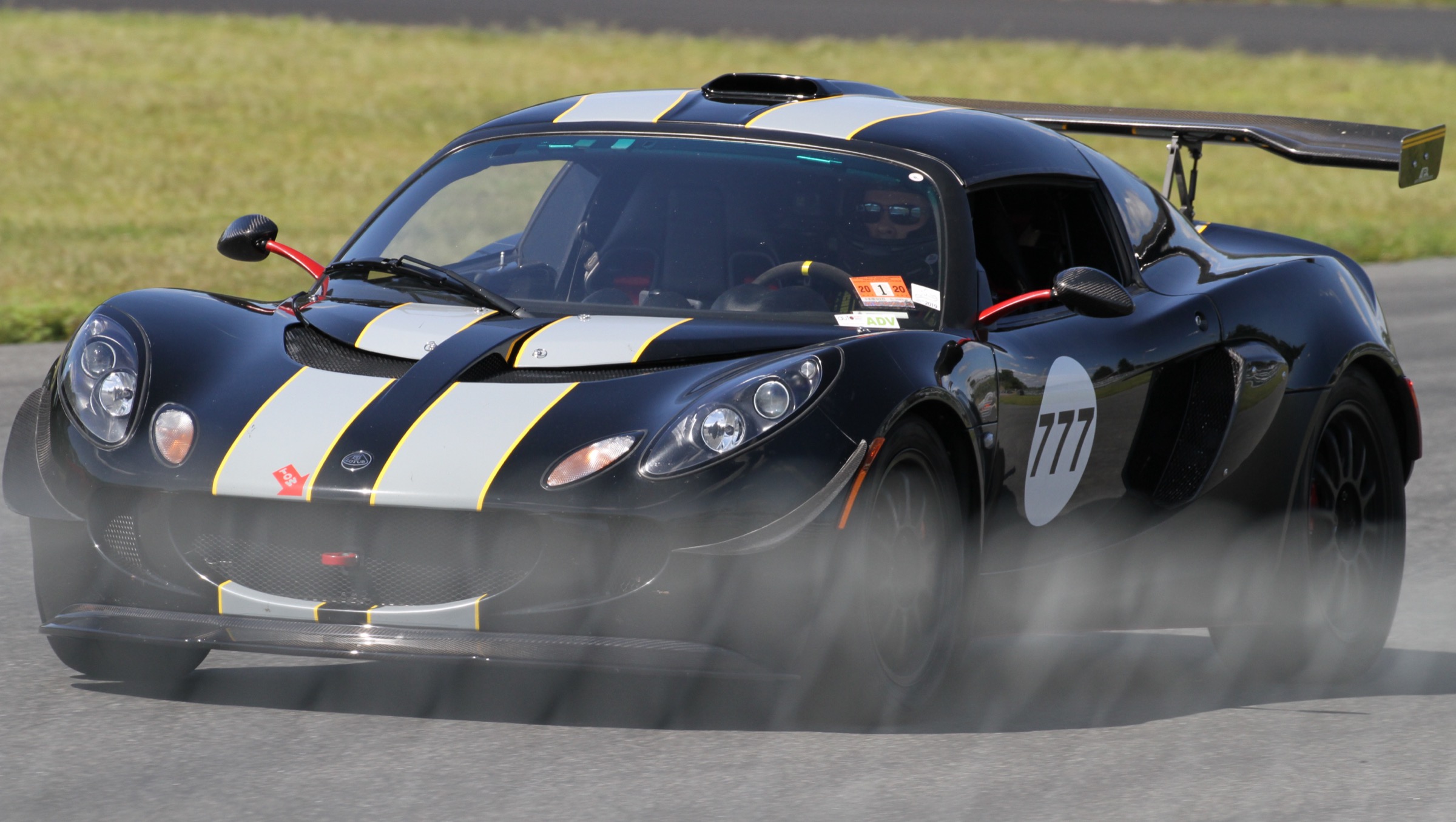 Black Lotus Exige S, number 777, cornering hard on a race track with dust kicking up